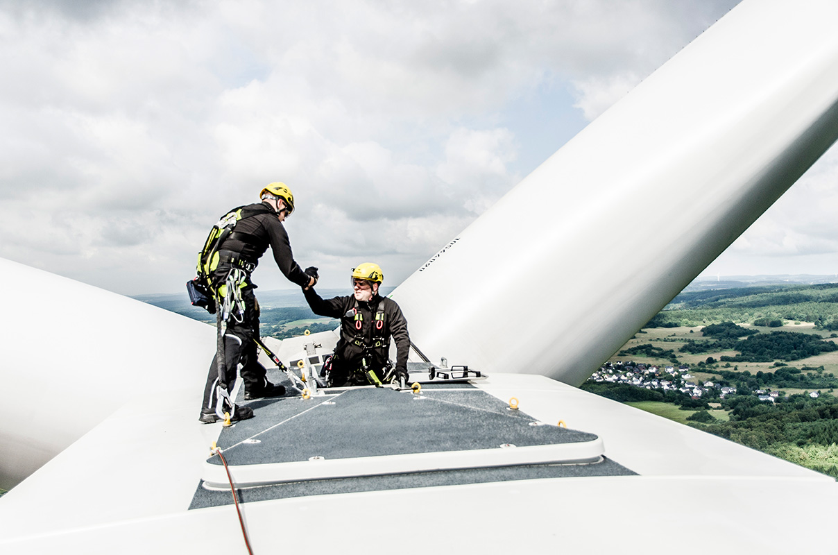 Zwei Servicetechniker arbeiten gesichert auf einer Windkraftanlage